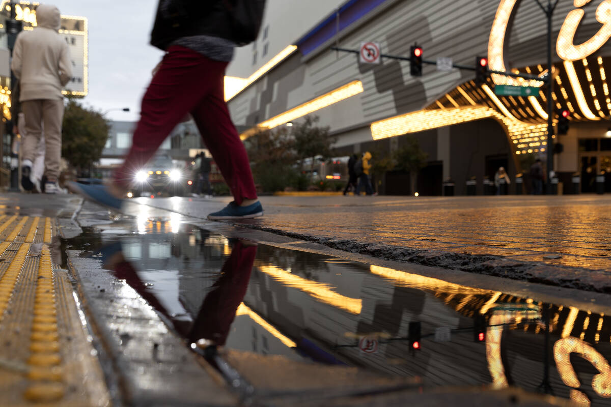 A pedestrian skips a puddle while crossing Main Street on Friday, Dec. 22, 2023, in downtown La ...