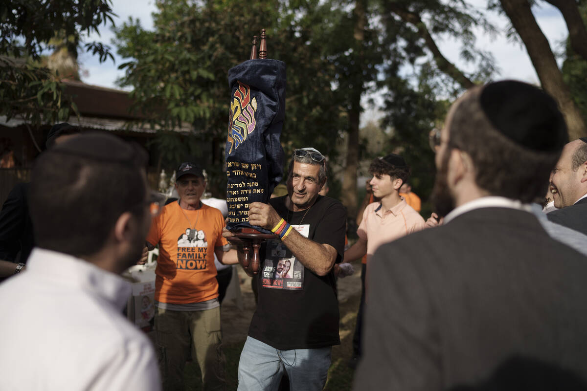 Eli Bibas holds a Torah scroll that survived the Holocaust during a ceremony marking the donati ...