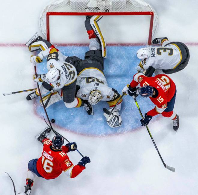 Golden Knights defenseman Shea Theodore (27) and Golden Knights goaltender Adin Hill (33) team ...