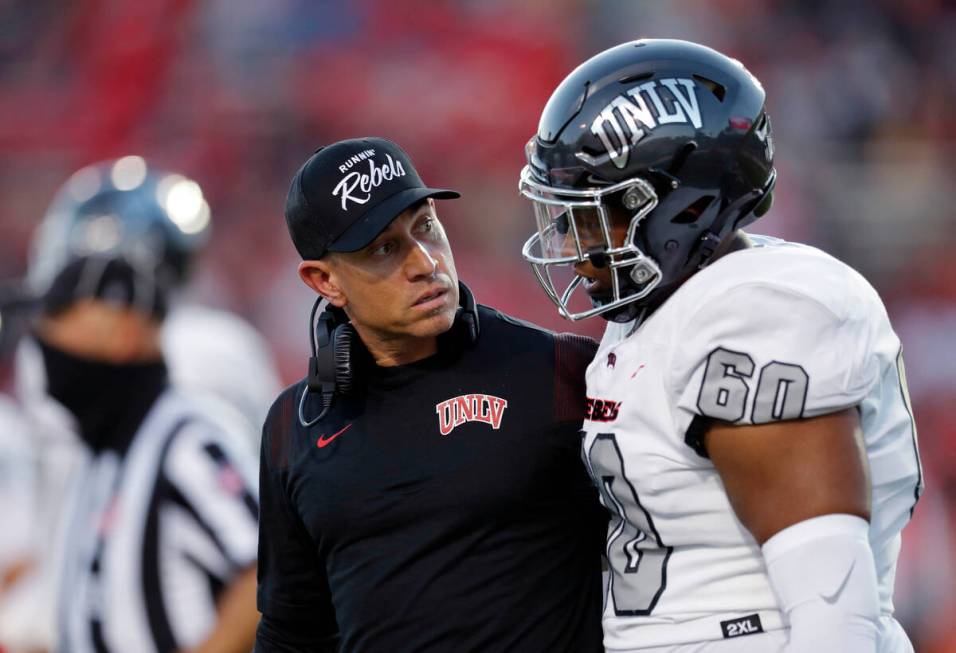 UNLV coach Marcus Arroyo listens to offensive lineman Amani Trigg-Wright during the first half ...