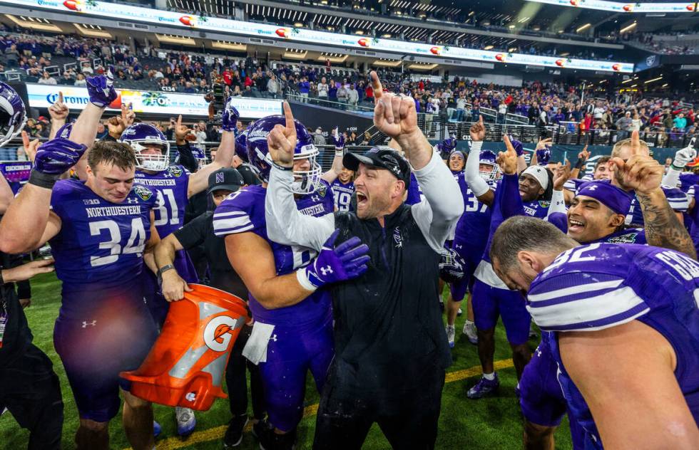 Northwestern Wildcats head coach David Braun celebrates their win after being doused with sport ...