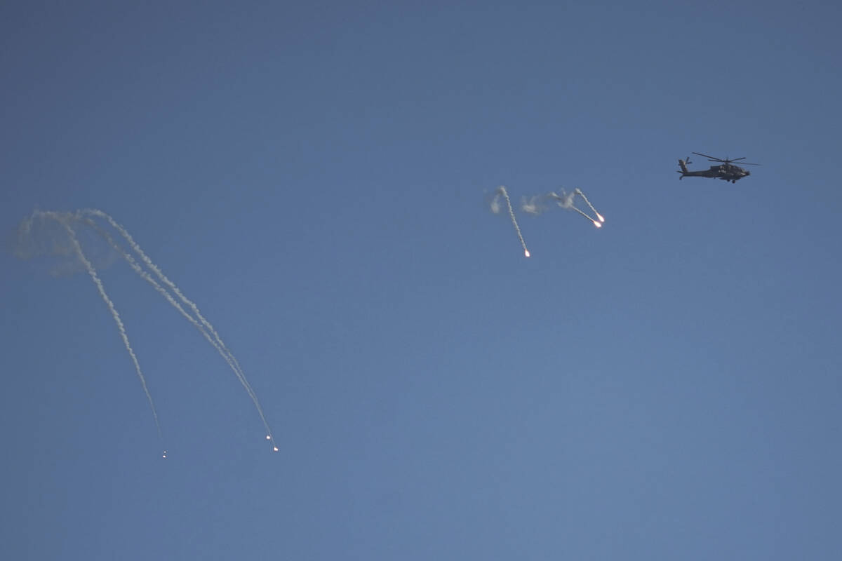 An Israeli Apache helicopter fires flares over the Gaza Strip, as seen from southern Israel, Su ...