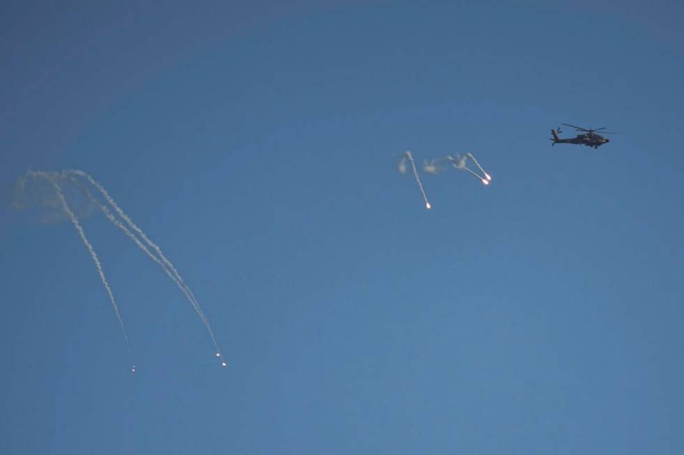 An Israeli Apache helicopter fires flares over the Gaza Strip, as seen from southern Israel, Su ...