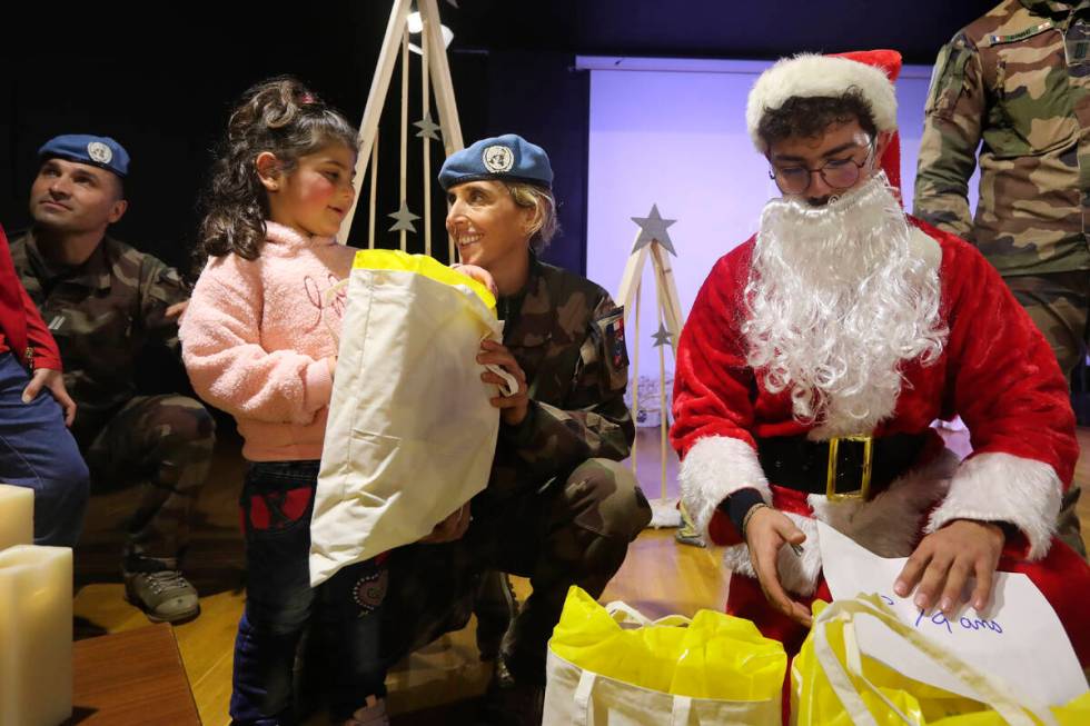 A U.N French peacekeeper, centre, gives a gift to a girl at Saint-Joseph des Saints-Coeurs Scho ...