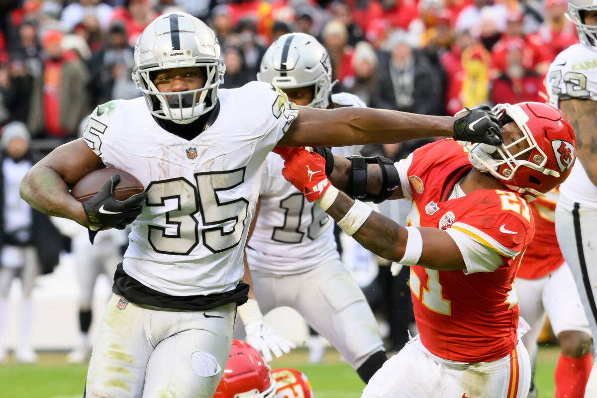 Las Vegas Raiders running back Zamir White (35) fights off Kansas City Chiefs safety Mike Edwar ...