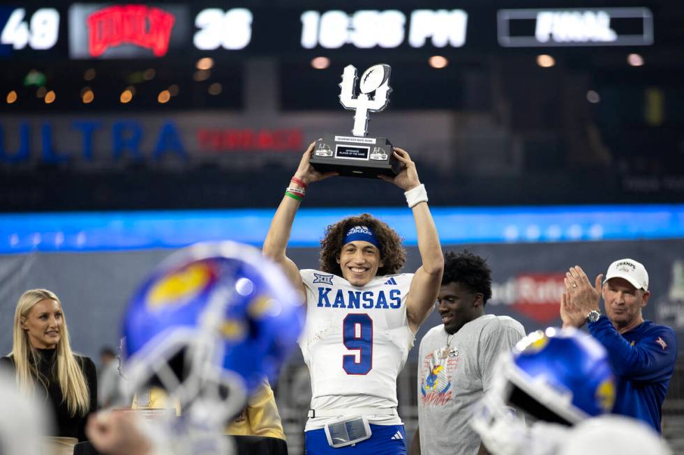 Kansas Jayhawks quarterback Jason Bean (9) holds up his Offensive Player of the Game trophy aft ...