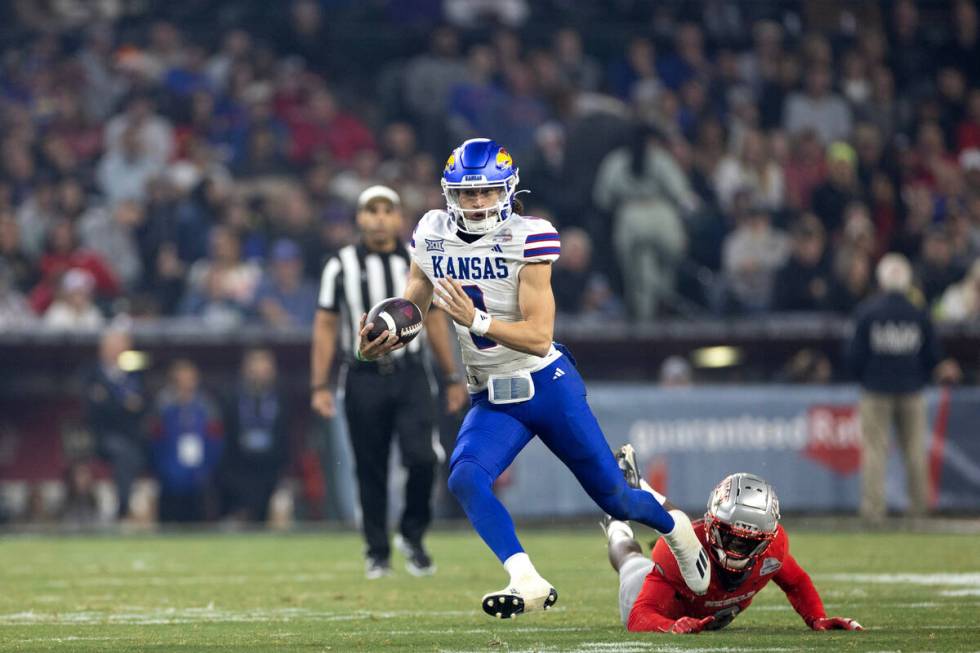 Kansas Jayhawks quarterback Jason Bean (9) runs the ball while UNLV Rebels defensive lineman Da ...