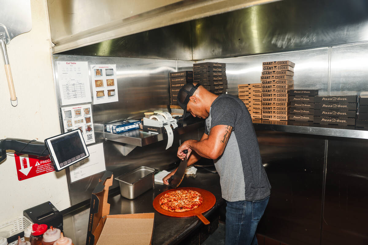 Co-owner Gabriel Jordan slices a pizza at Pizza Guys, a California-based pizza restaurant chain ...