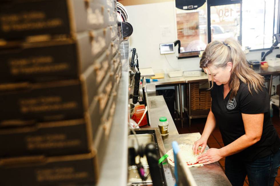 Co-owner Kellie Jordan slices a pizza at Pizza Guys, a California-based pizza restaurant chain, ...