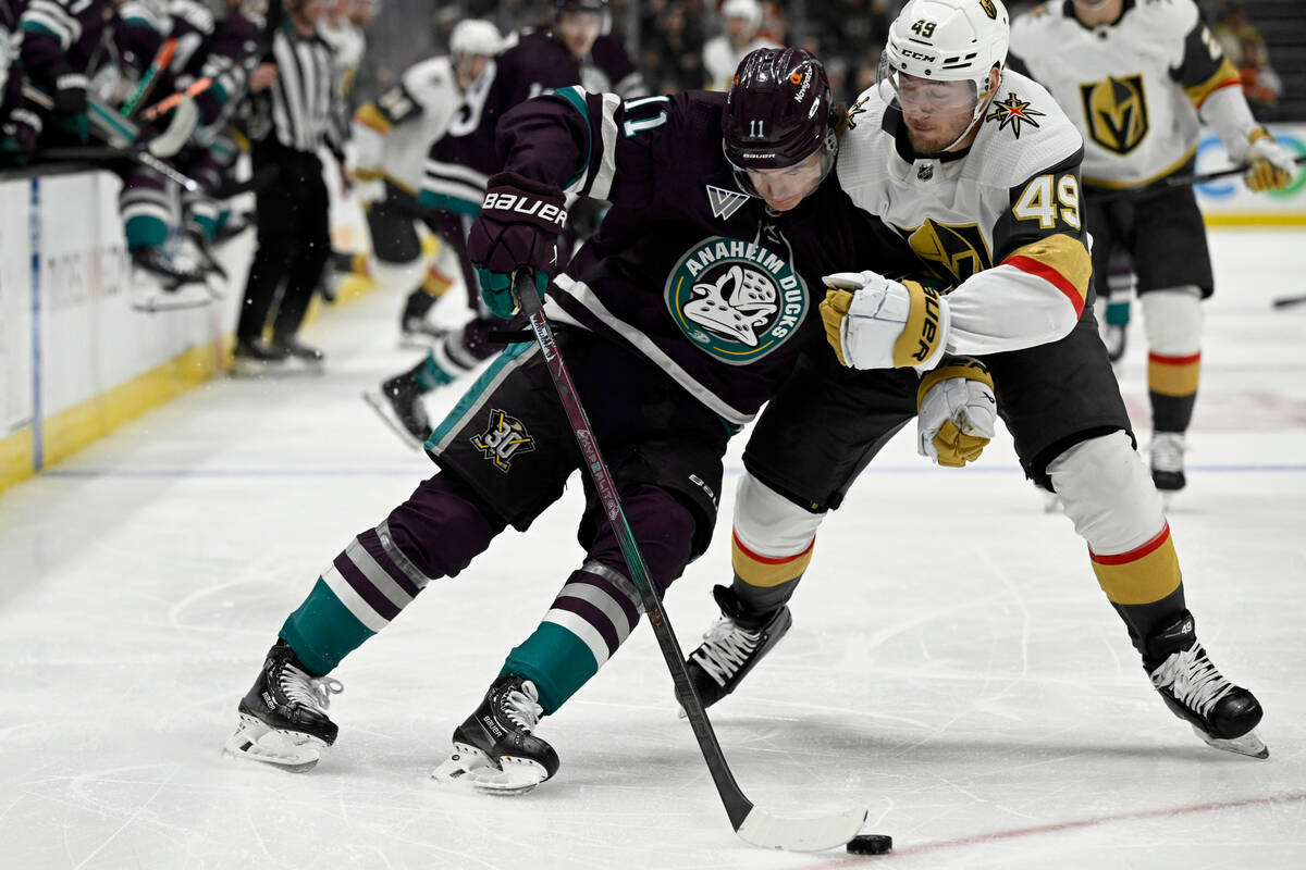 Anaheim Ducks center Trevor Zegras, left, controls the puck while leaning against Vegas Golden ...