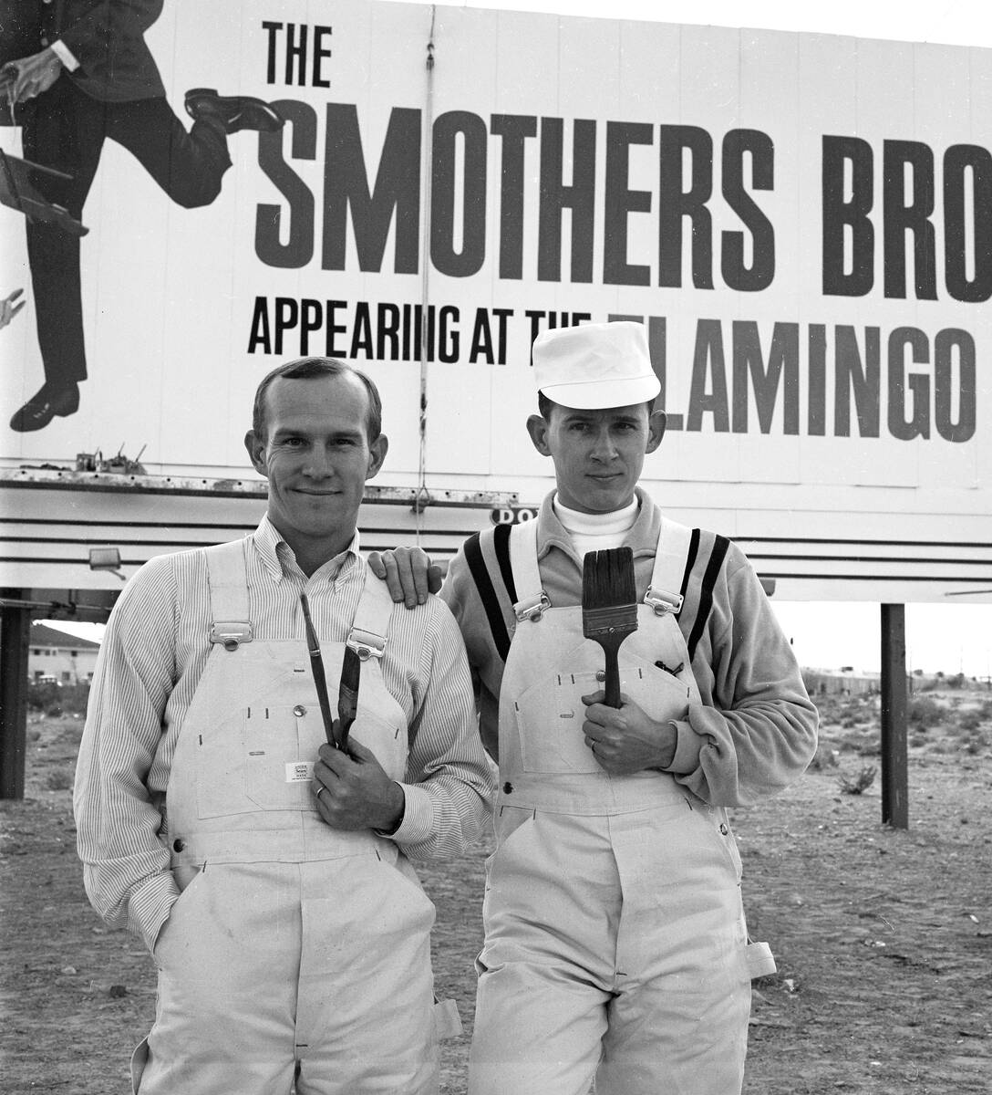 Tom, left, and Dick Smothers pose as painters next to a billboard on the Las Vegas Strip advert ...