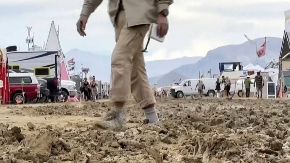 A man walks through mud at the Burning Man festival site in Black Rock, Nev., on Monday, Sept. ...