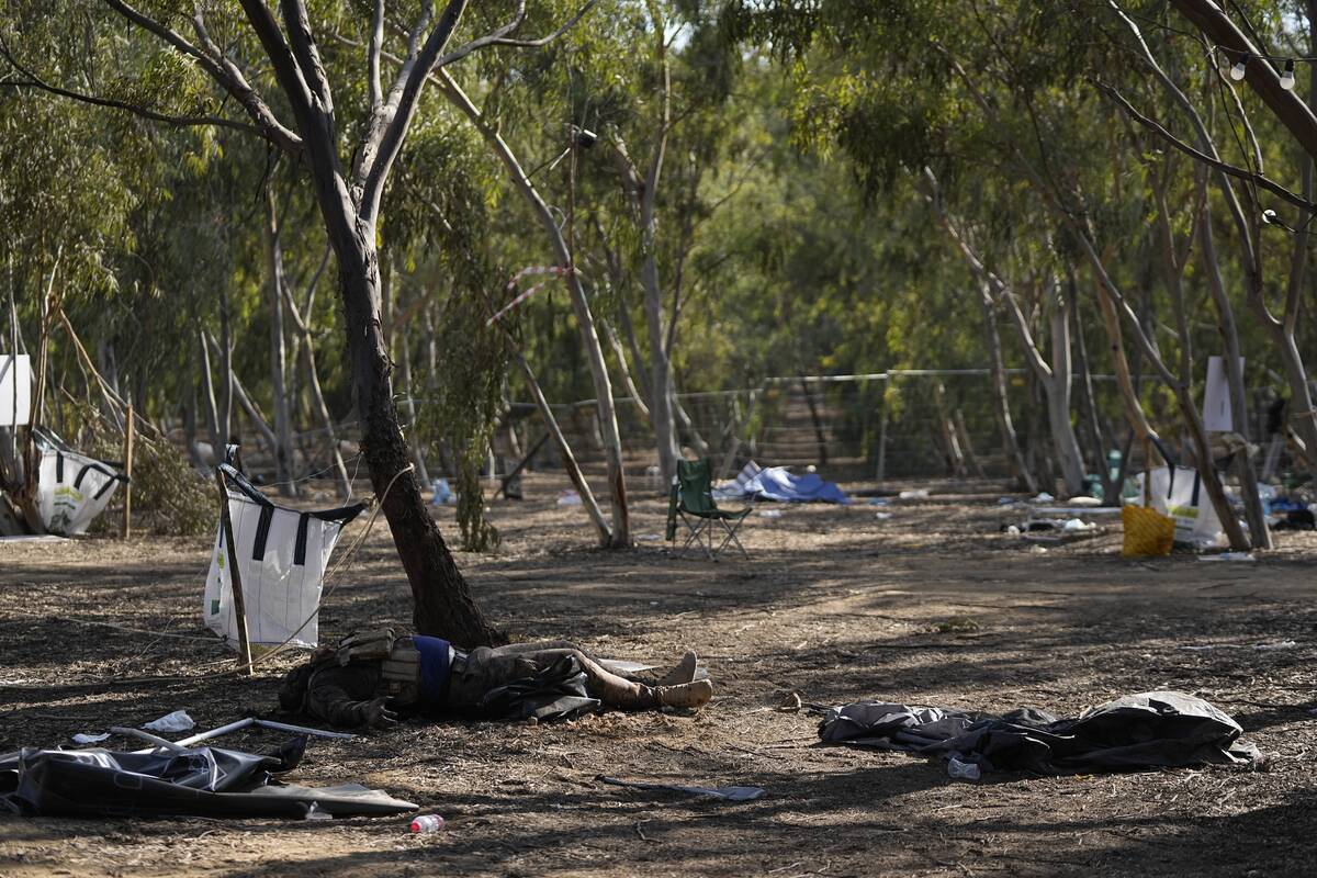 FILE - The body of a killed Hamas militant lies on the ground at the site of a music festival, ...