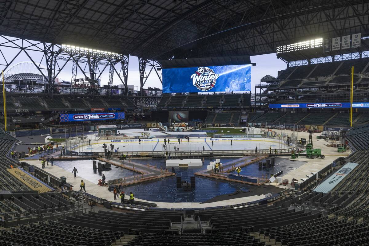An ice crew adds lines and logos to the NHL Winter Classic ice skating rink at T-Mobile Park in ...