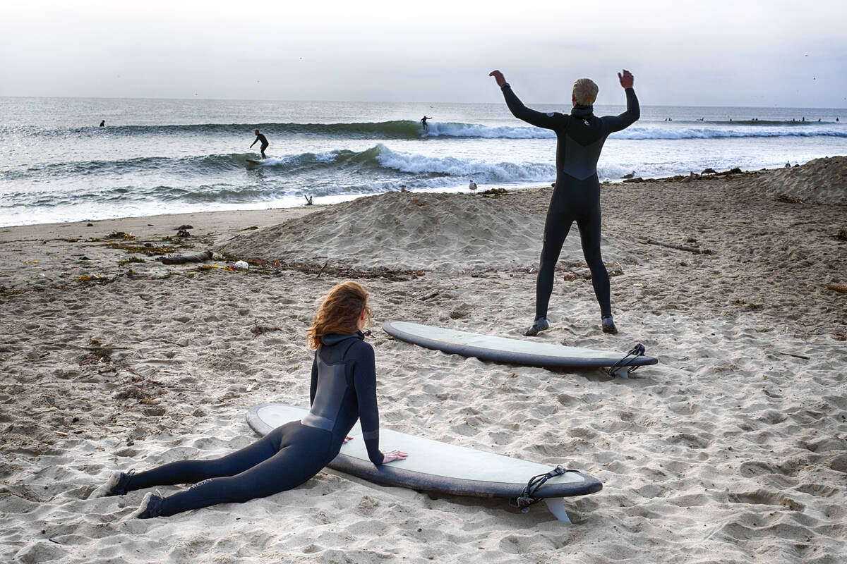 Surfers stretch before heading out to the surf in Malibu Beach, Calif. on Friday, Dec. 29, 2023 ...