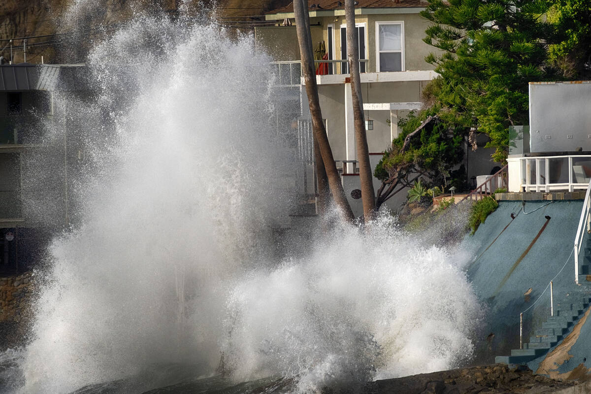 Waves smash against a sea wall next to homes along the California coast in Malibu Beach, Calif. ...