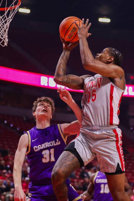 UNLV Rebels guard Luis Rodriguez (15) shoots a layup as Carroll College Fighting Saints guard J ...