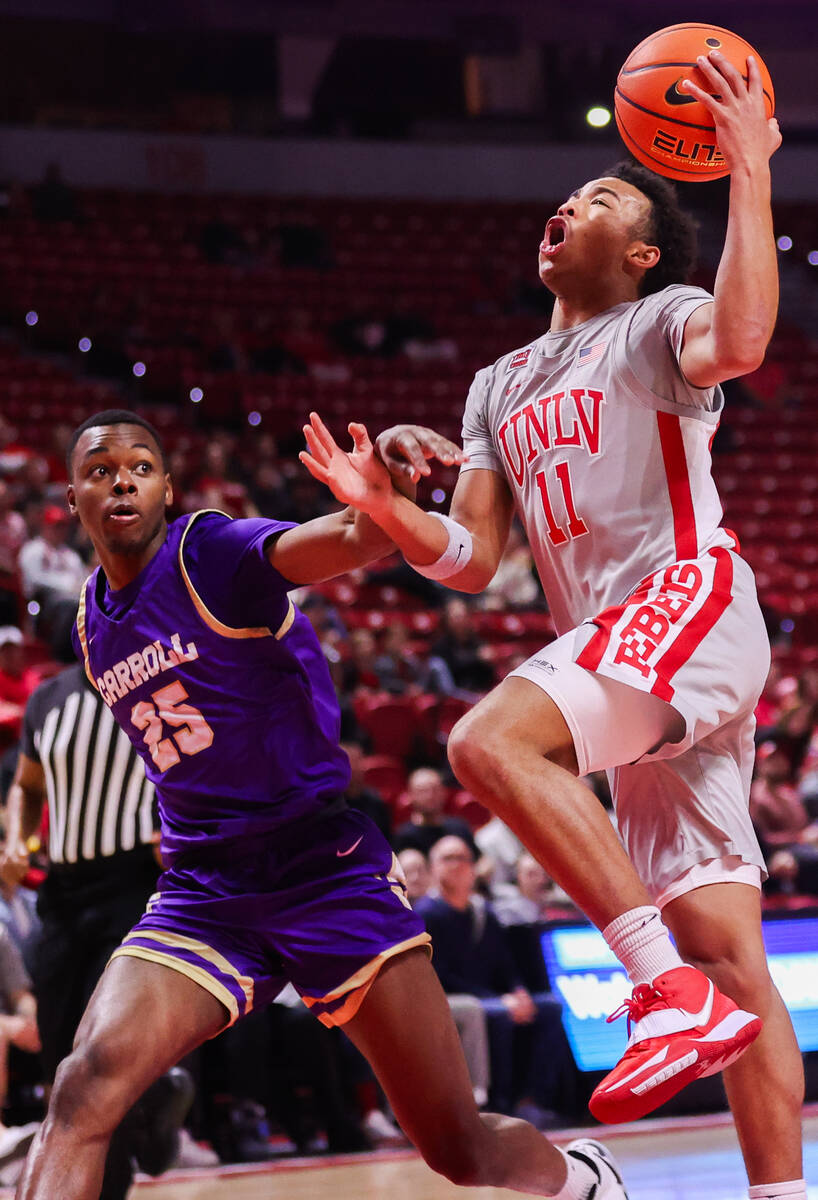 UNLV Rebels guard Dedan Thomas Jr. (11) goes in for a layup around Carroll College Fighting Sai ...