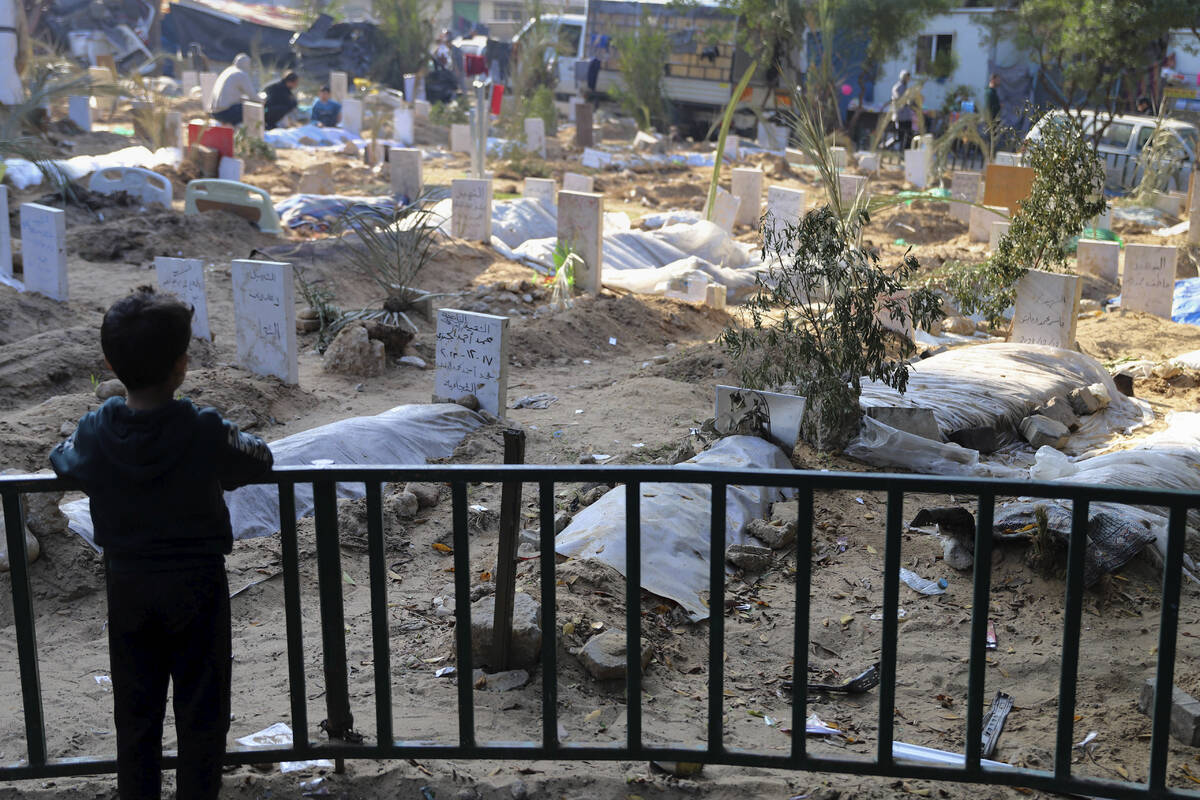 A Palestinian child looks at the graves of people killed in the Israeli bombardment of the Gaza ...