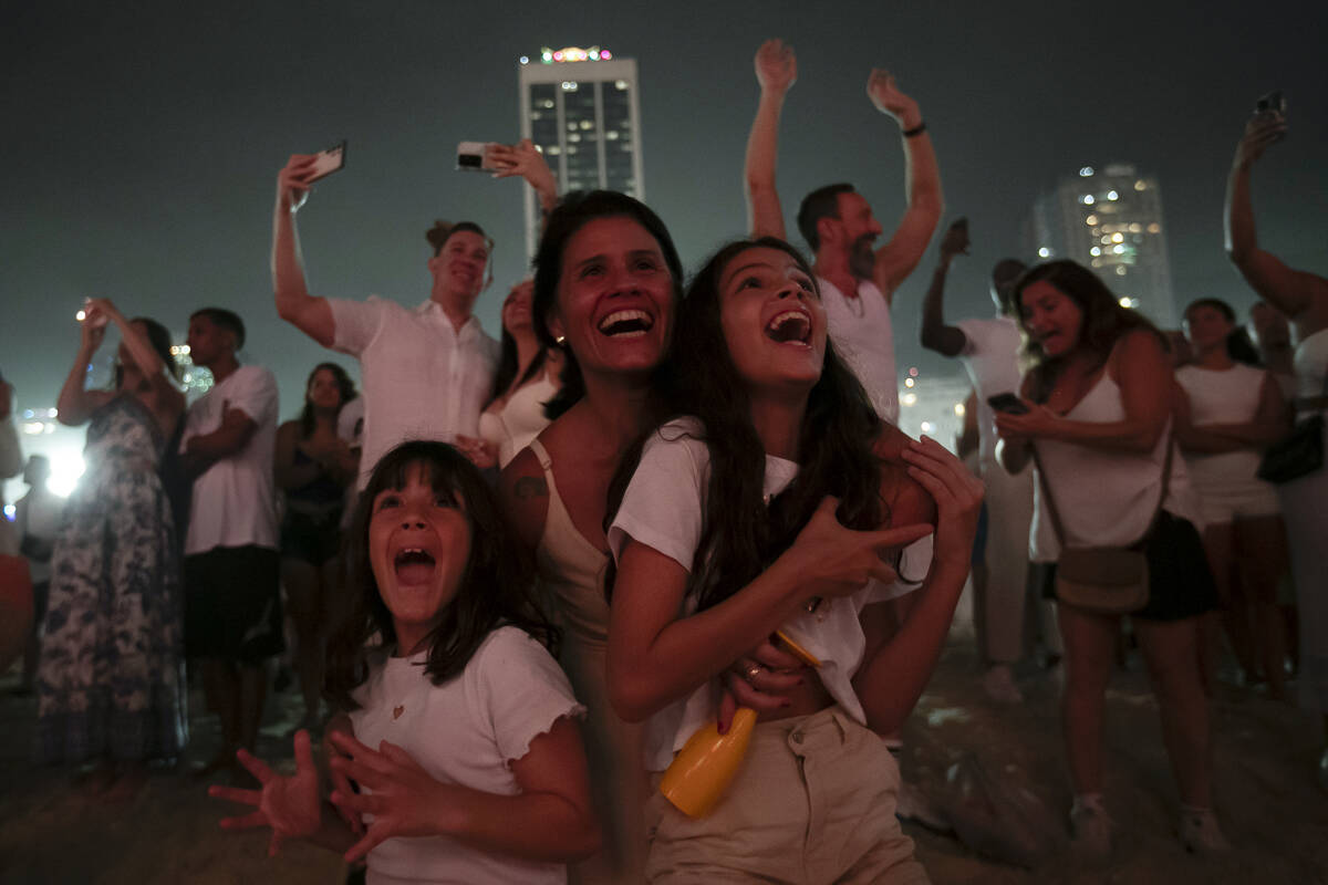 People react as they watch fireworks light up Copacabana Beach during New Year's celebrations i ...