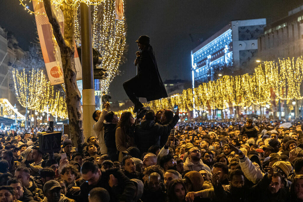 A reveler climbs onto a pole during New Year's celebrations in Paris, France, Sunday, Dec. 31, ...