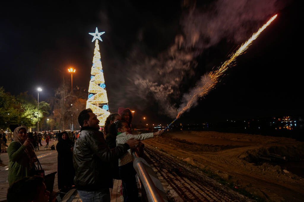 An Iraqi boy lights fireworks mark New Year's Eve in Baghdad, Iraq, Sunday, Dec. 31, 2023. (AP ...