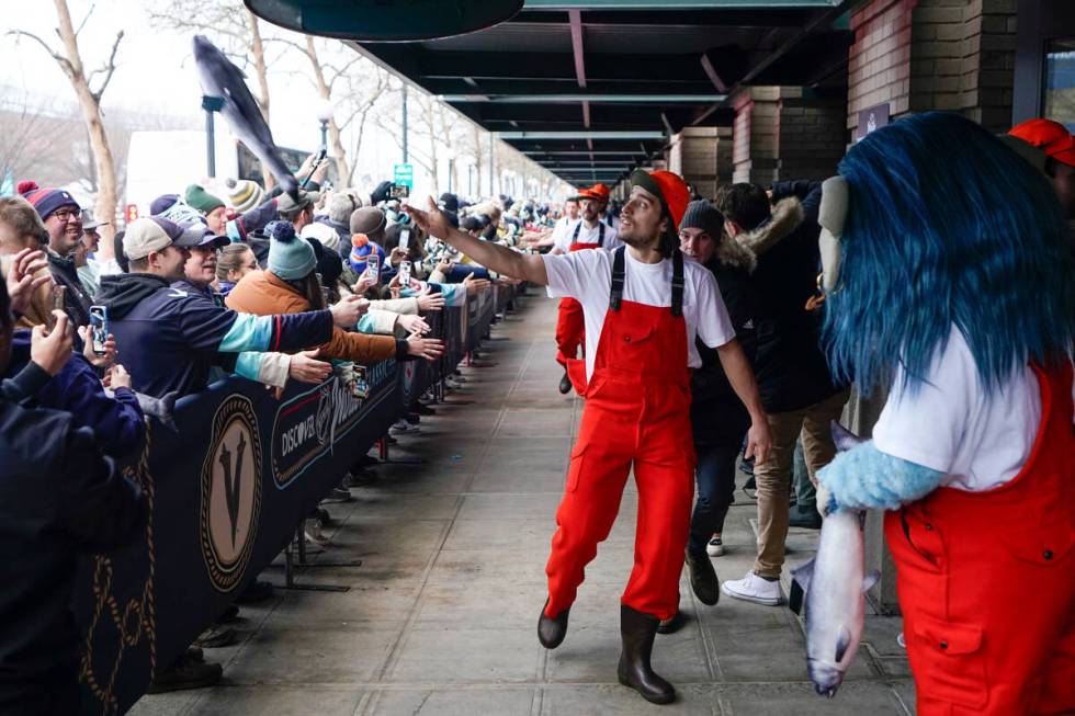 Seattle Kraken left wing Brandon Tanev throws a fish to fans as he arrives with teammates dress ...