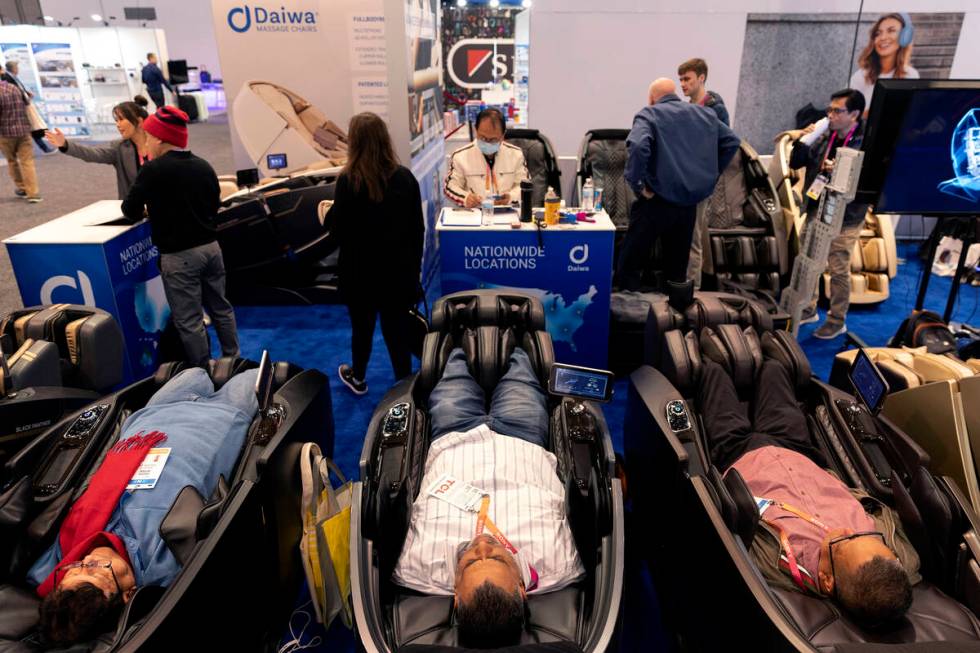 Attendees relax in Daiwa massage chairs at the company’s booth during the CES tech show ...