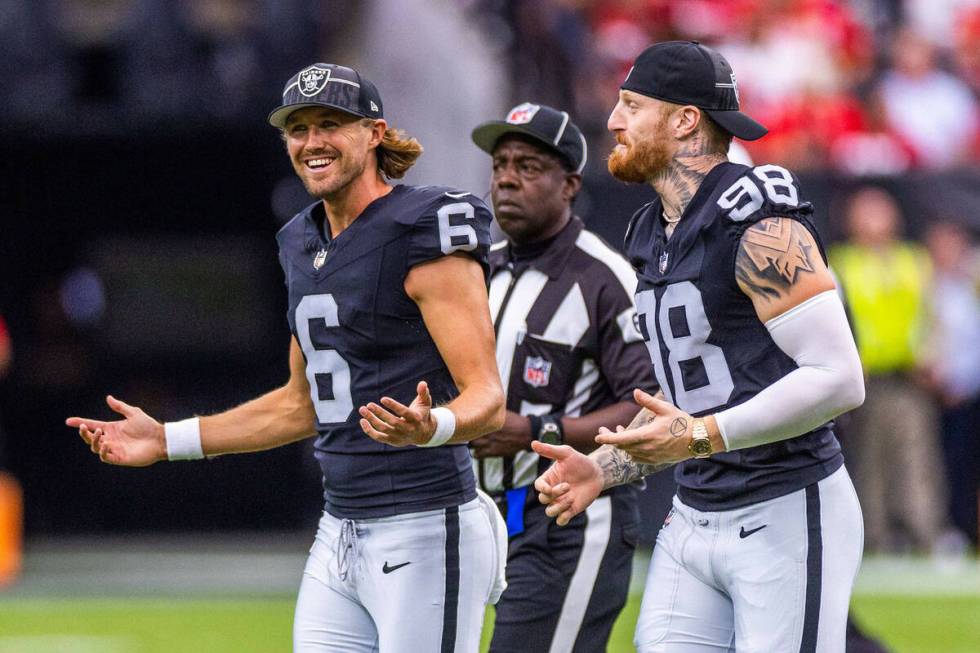 Raiders punter AJ Cole (6) and defensive end Maxx Crosby (98) run off the field after the coin ...