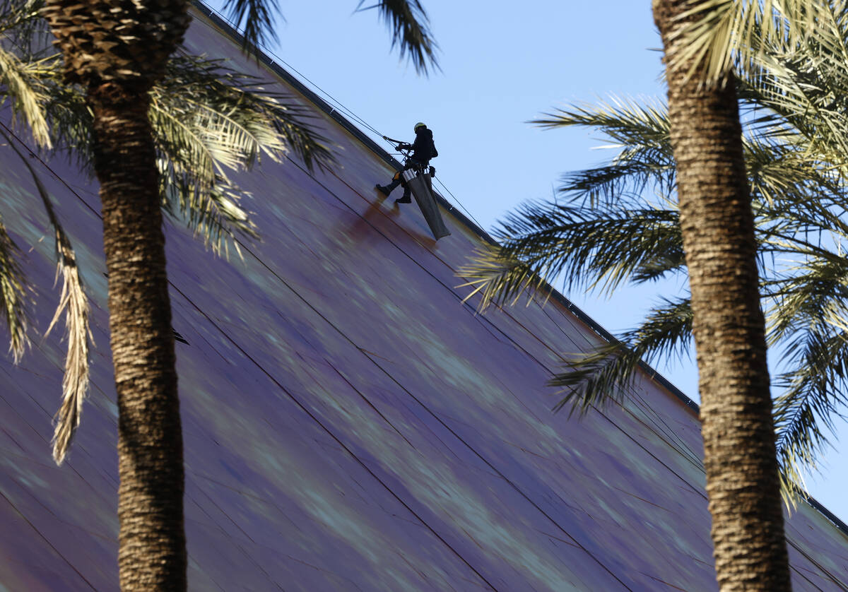 A worker wraps the east side of the Luxor with the Doritos ad, on Thursday, Jan. 4, 2024, in La ...