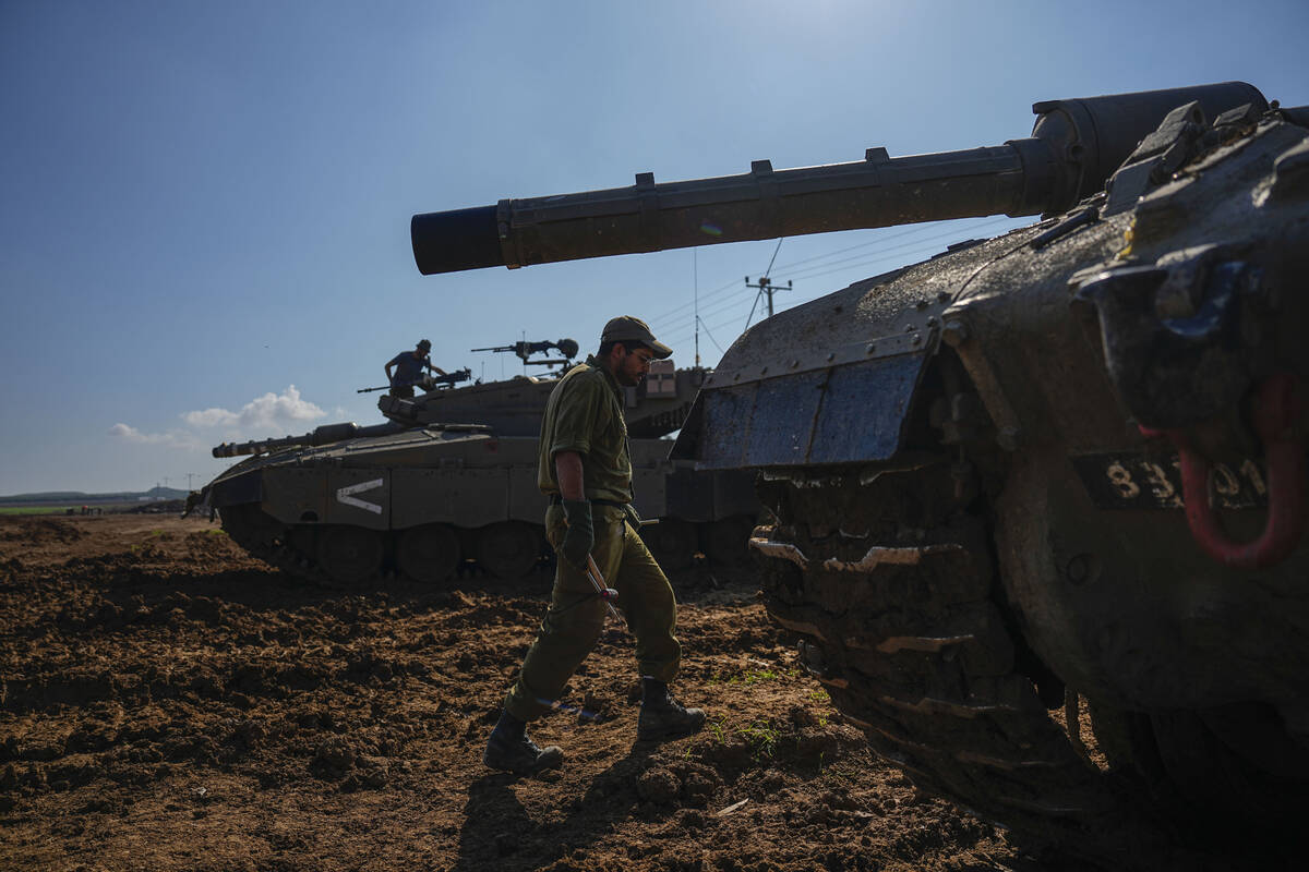 Israeli soldiers work on their tank in a staging area at the Israeli-Gaza border in southern Is ...