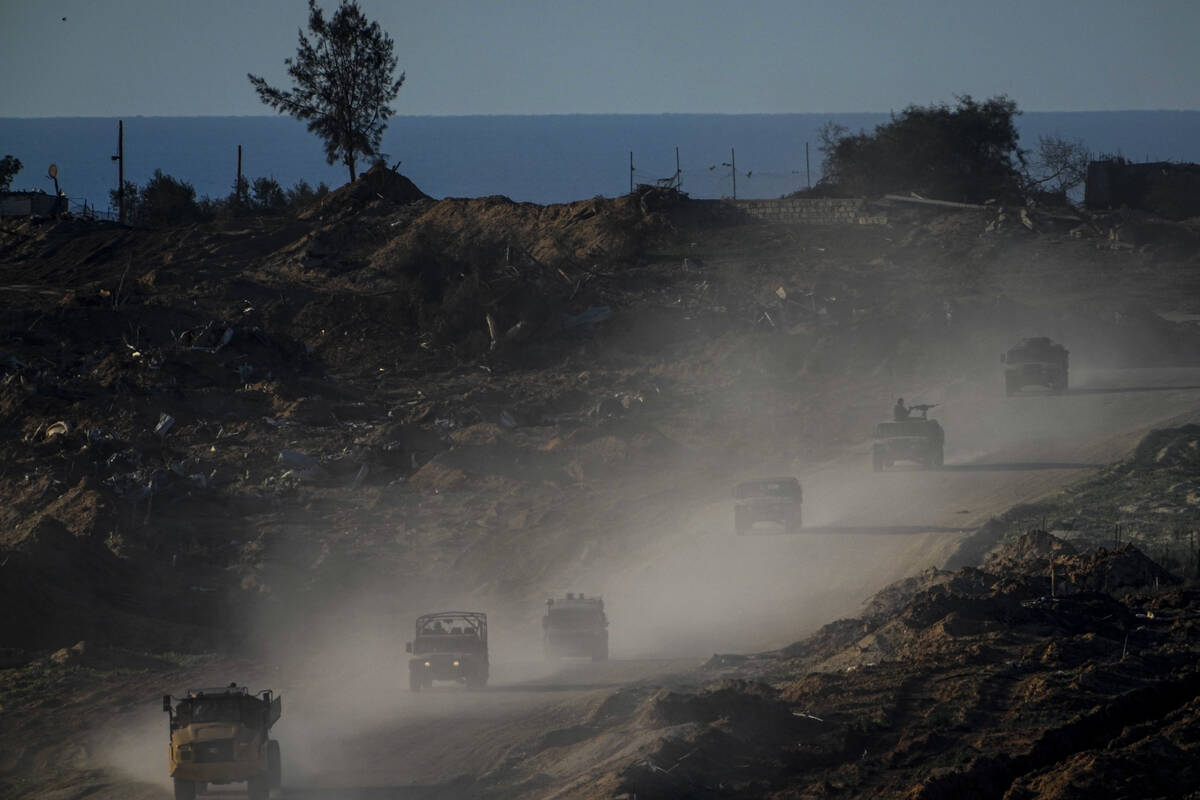 A convoy of Israeli troops moves in the Gaza Strip as seen from southern Israel, Thursday, Jan. ...