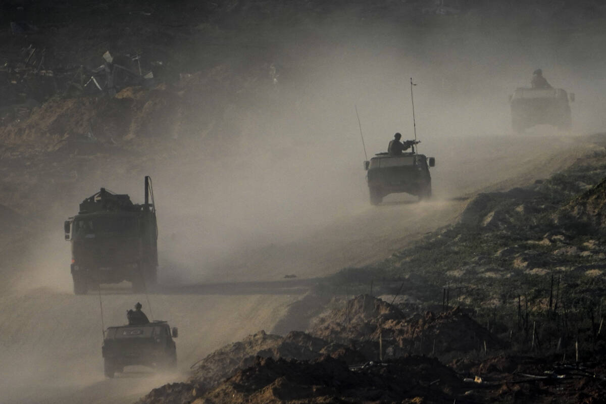 A convoy of Israeli troops moves in the Gaza Strip as seen from southern Israel, Thursday, Jan. ...