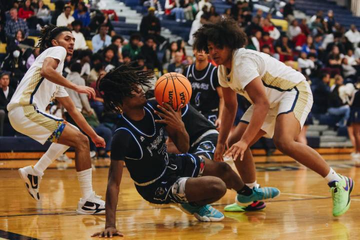 Desert Pines forward Damonte Duhart (3) falls to the ground as he fights to keep hold of the ba ...