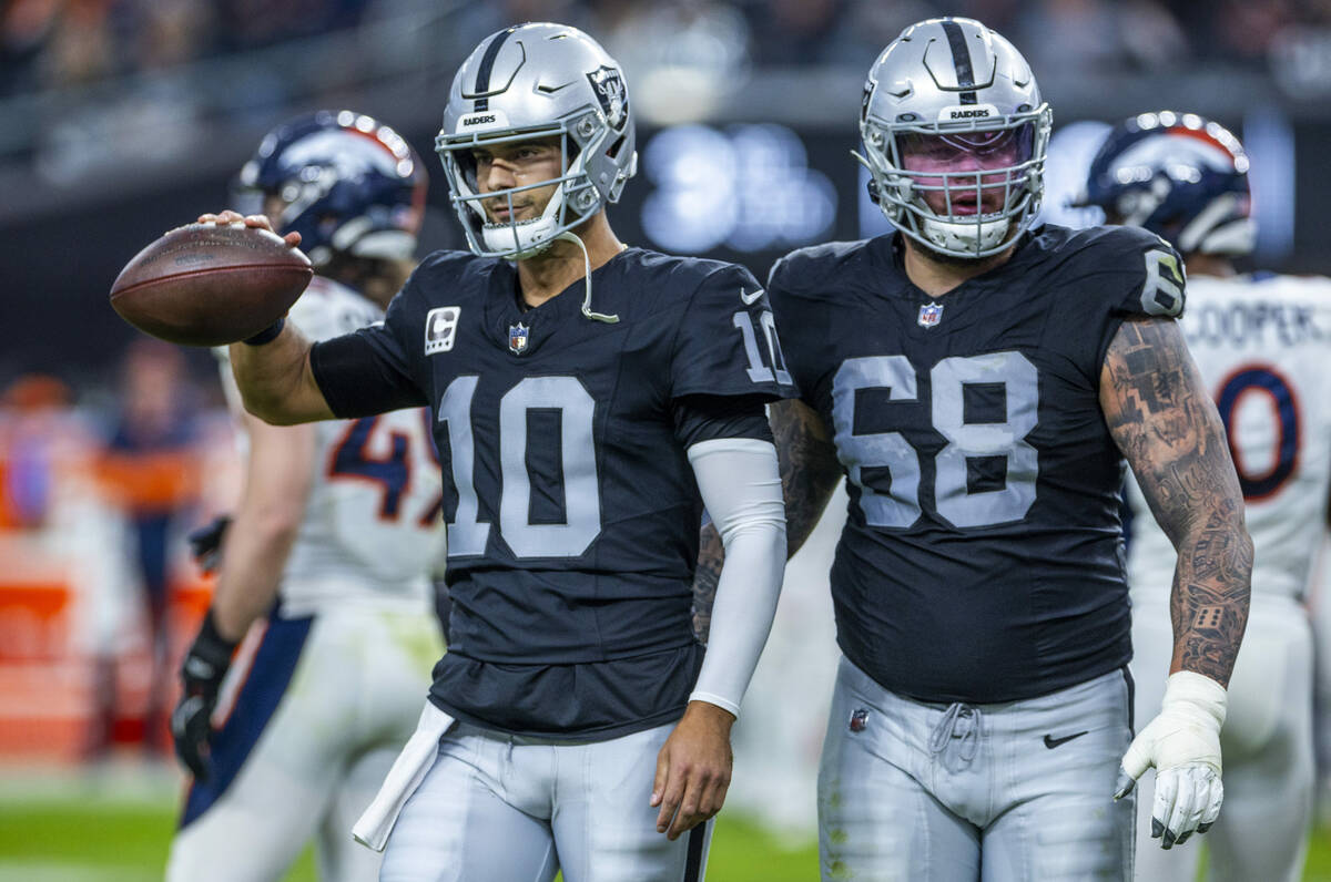 Raiders quarterback Jimmy Garoppolo (10) walks off the field with center Andre James (68) again ...