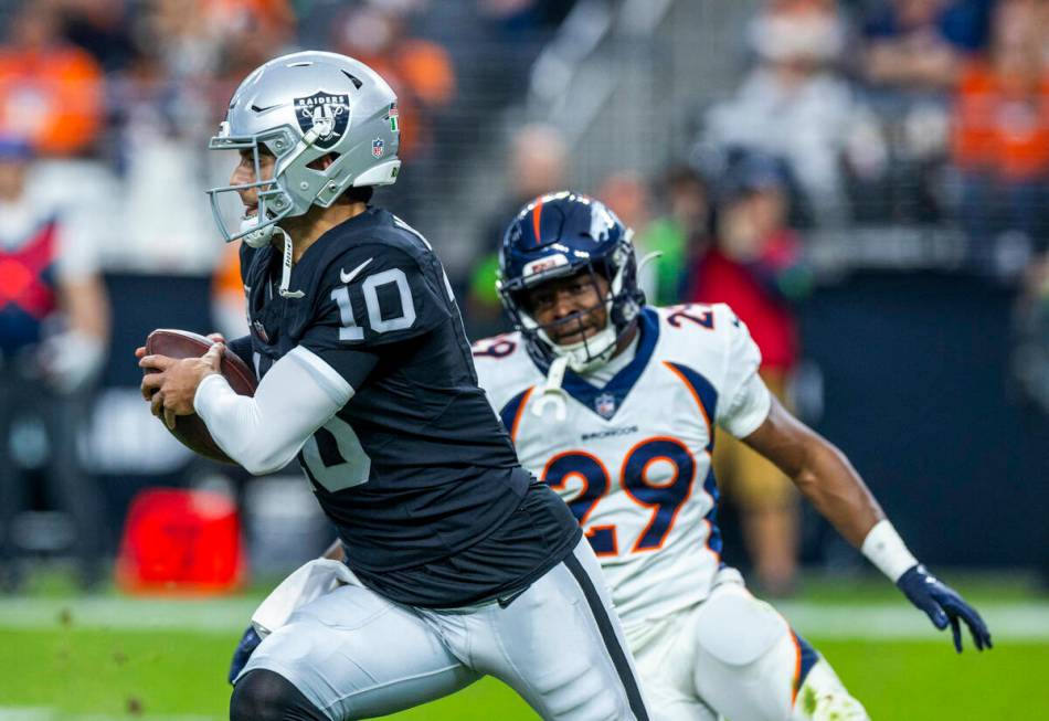 Raiders quarterback Jimmy Garoppolo (10) looks for some yards while pursued by Denver Broncos c ...