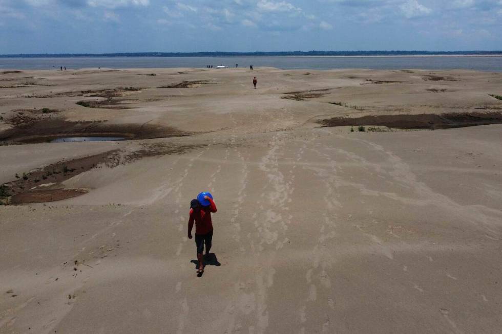 FResidents of a riverside community carry food and containers of drinking water from an aid dis ...