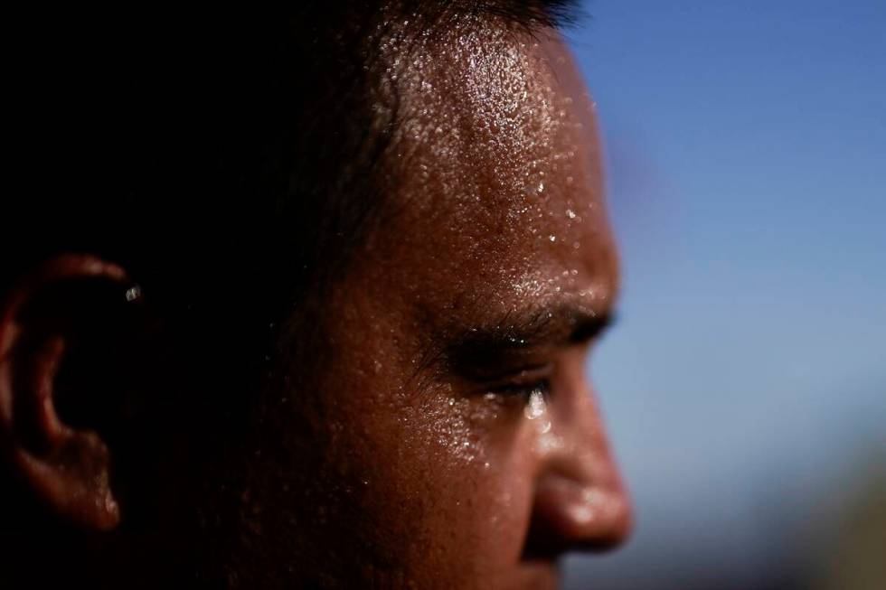 Sweat covers the face of Juan Carlos Biseno after dancing to music from his headphones as after ...