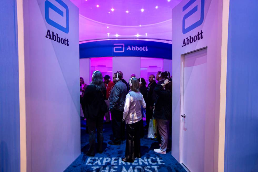 Attendees take a tour of the Abbott booth during the first day of CES at the Las Vegas Conventi ...