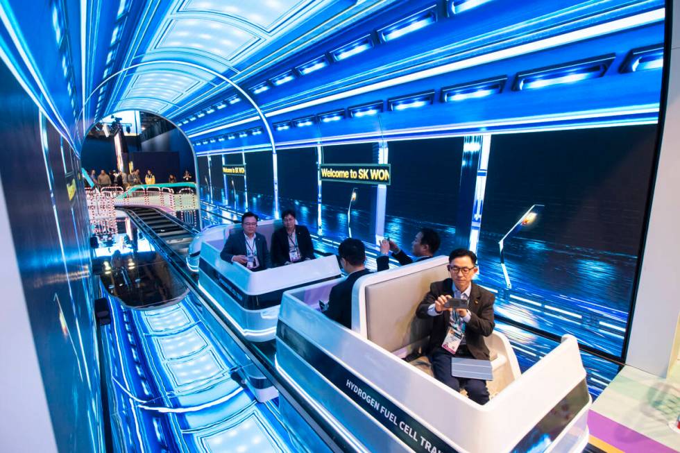 Attendees ride on a hydrogen fuel cell train at the SK Group booth during the first day of CES ...