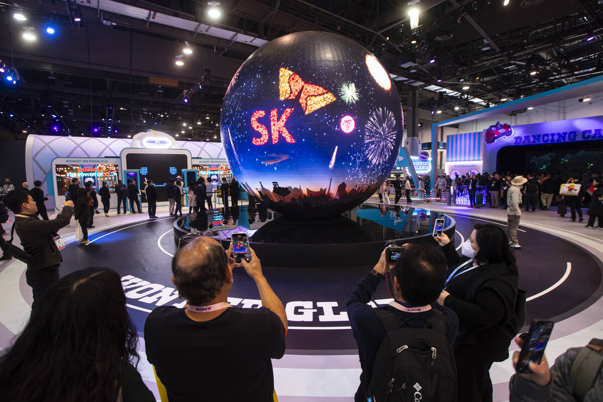 Attendees record the spherical LED “Wonder Globe” at the SK Group booth during th ...