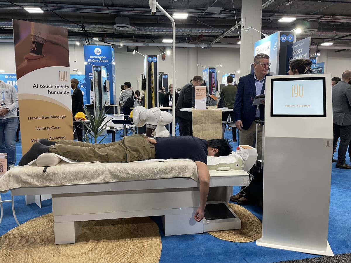 A conventioneer receives a back massage from iYU Spa, an AI-supported massager from French star ...