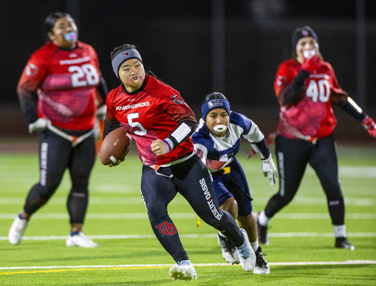 Desert Oasis quarterback Akemi Higa (5) runs for yards pas Shadow Ridge defender Jimena Barraza ...