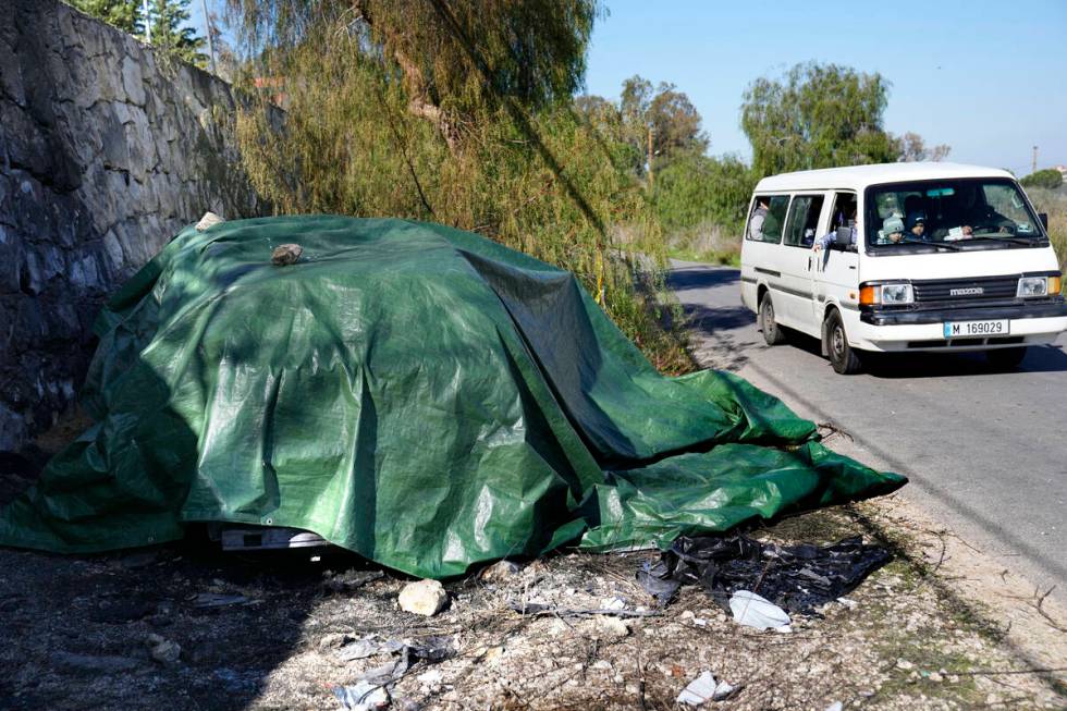 A school bus passes by the covered burned and damaged car that was used by the senior Hezbollah ...