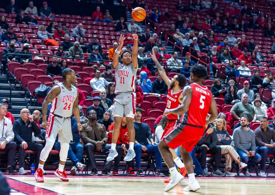 UNLV guard Dedan Thomas Jr. (11) gets off a 3-point basket attempt over New Mexico Lobos guard ...