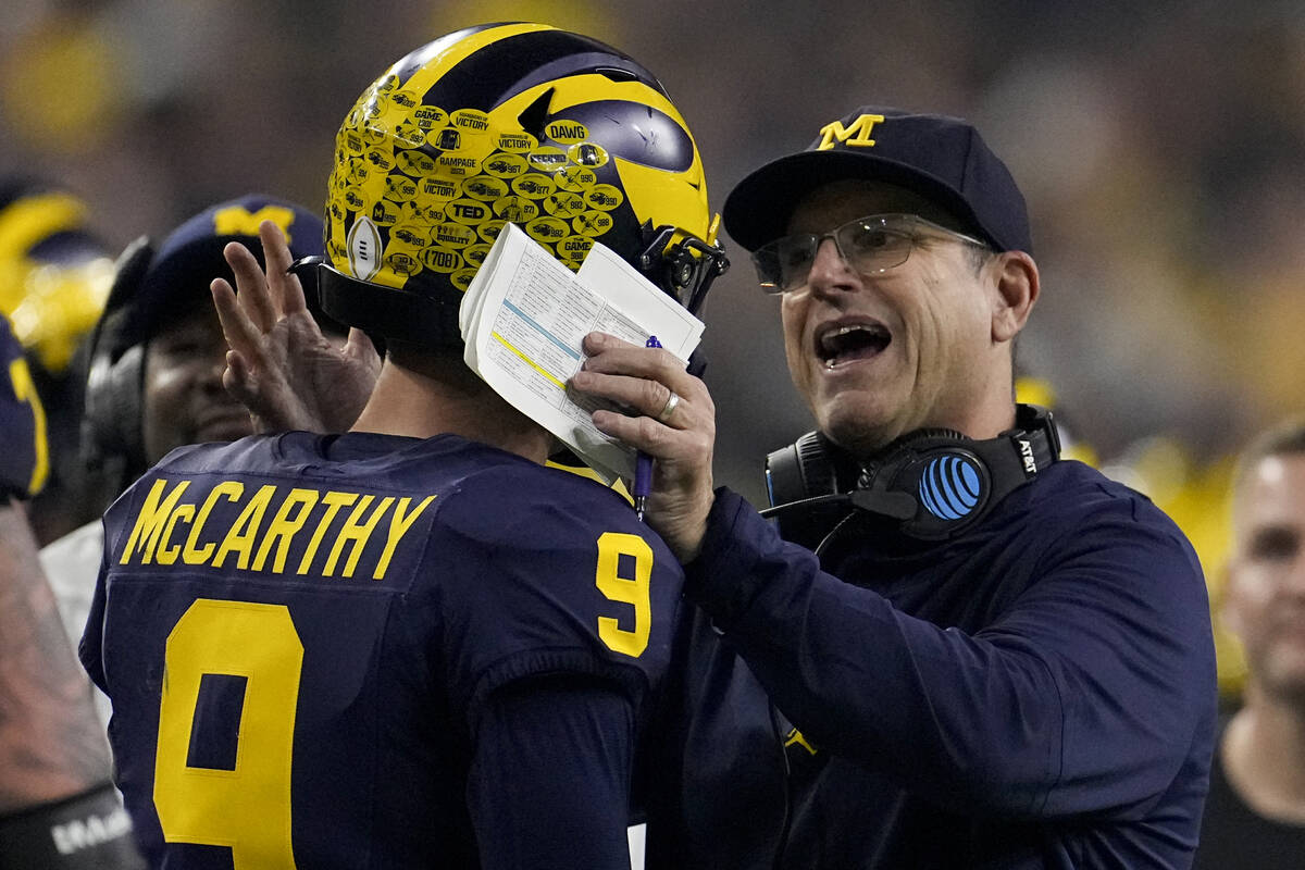 Michigan head coach Jim Harbaugh takes with quarterback J.J. McCarthy during the first half of ...