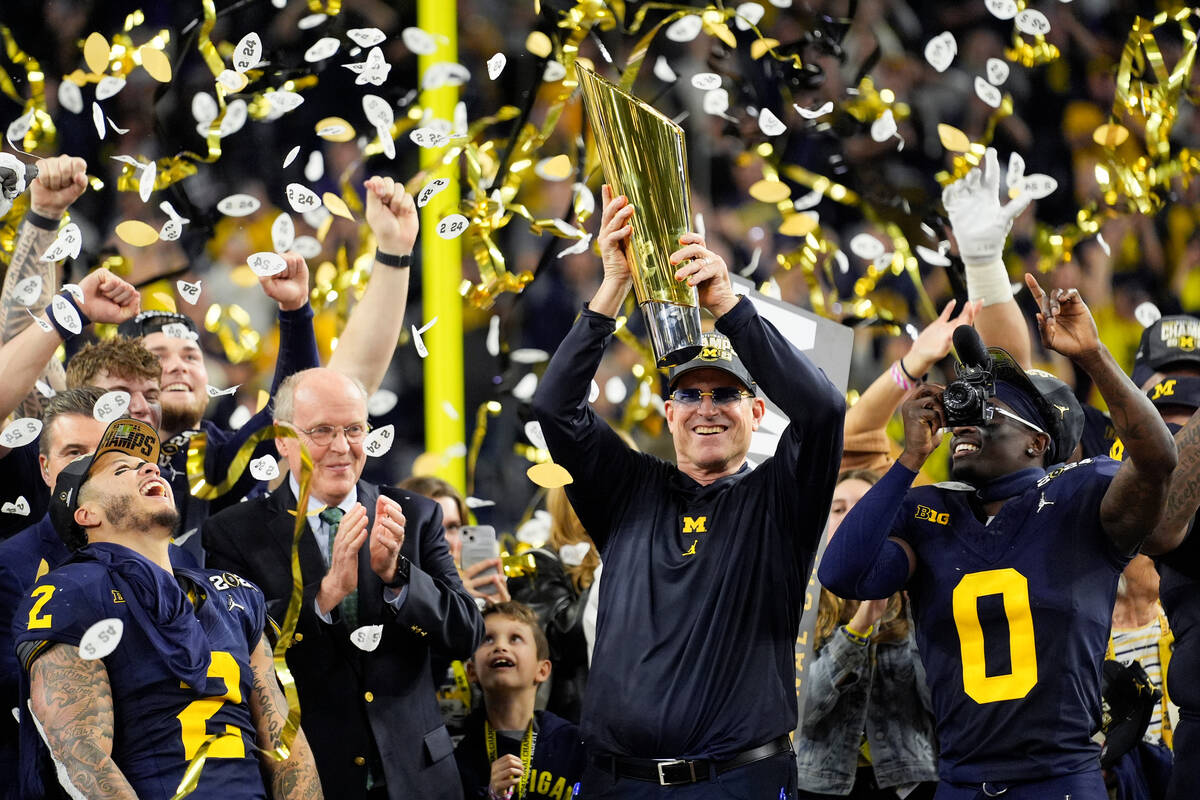Michigan head coach Jim Harbaugh celebrates with the trophy after their win in the national cha ...