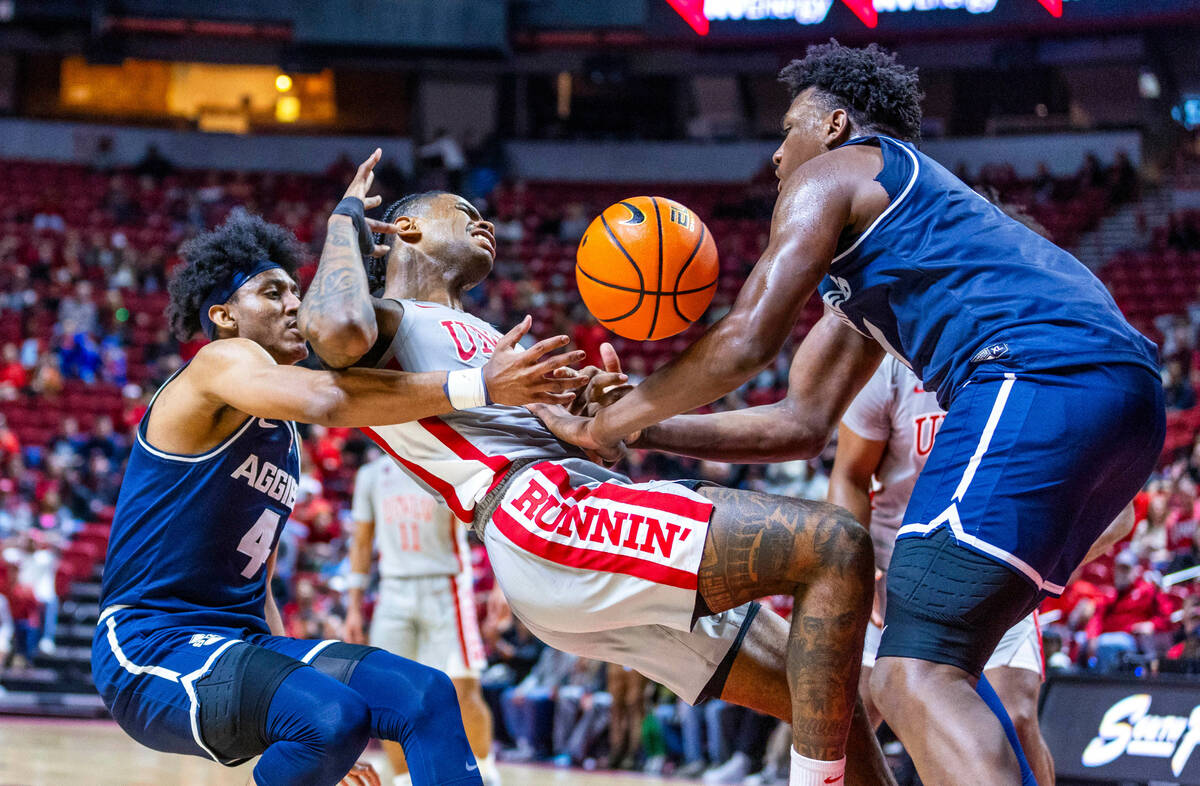 UNLV guard Luis Rodriguez (15) is fouled hard by both Utah State Aggies guard Ian Martinez (4) ...