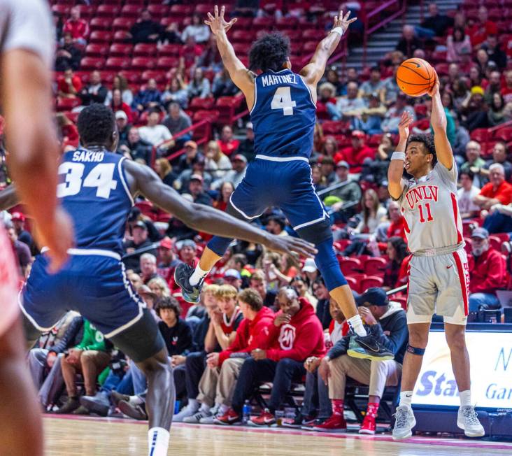 UNLV guard Dedan Thomas Jr. (11) looks to pass as Utah State Aggies guard Ian Martinez (4) leap ...