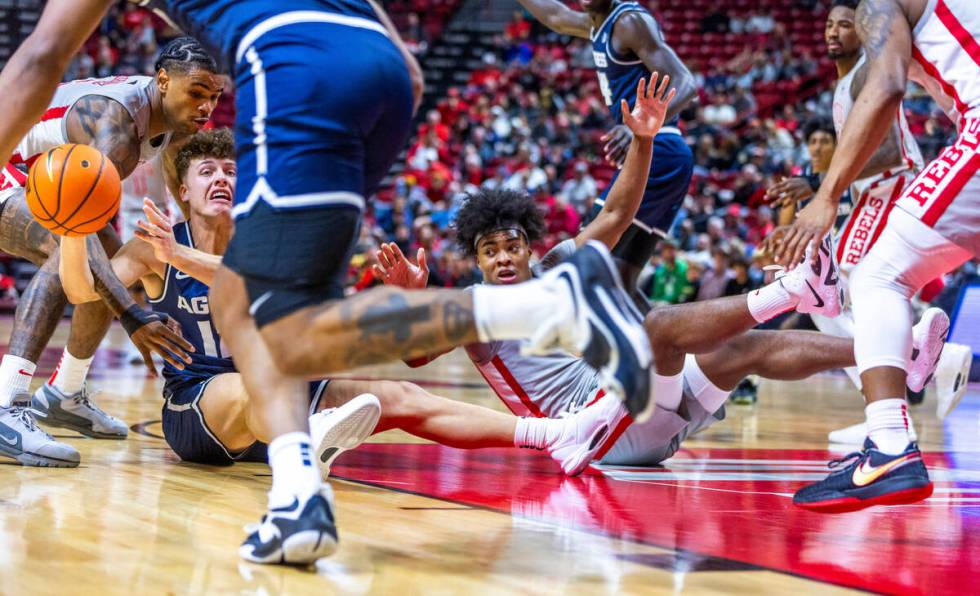 Utah State Aggies guard Mason Falslev (12) looks to pass while surrounded by UNLV guard Luis Ro ...